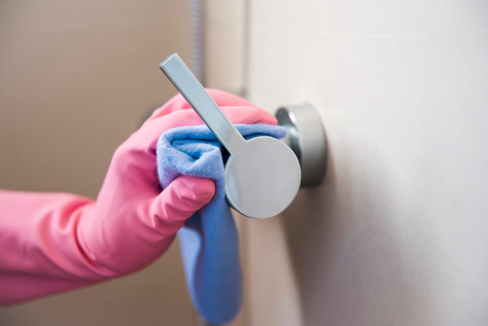 Hand mit Handschuh reinigt eine Türklinke – Hygiene in der Ordination